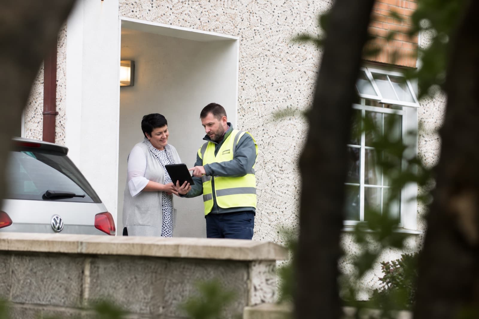 Illustrative scene of a resident reviewing service information with a technician outside a home